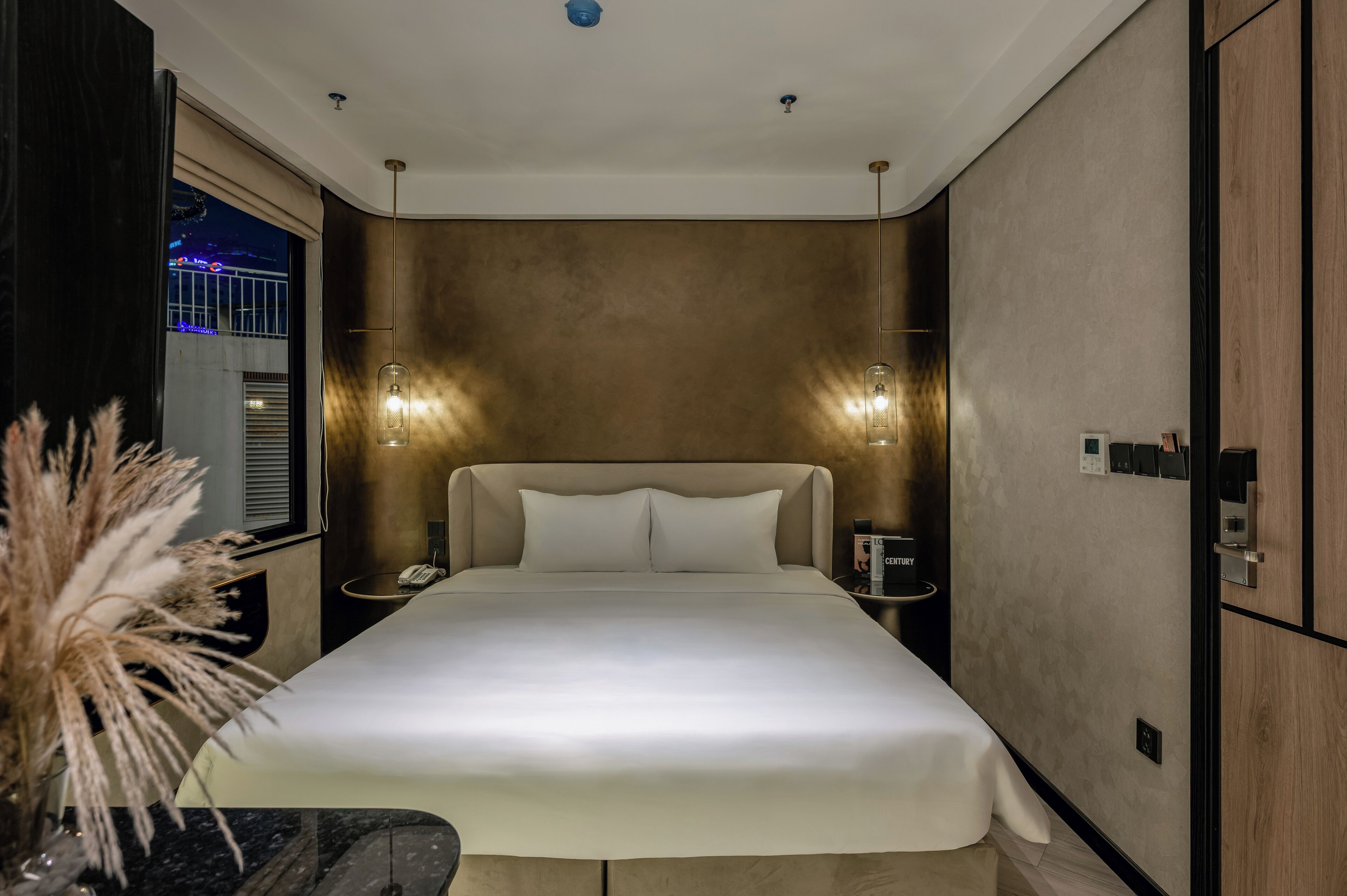 A modern hotel room with a large bed, bedside tables, and a nightstand.
