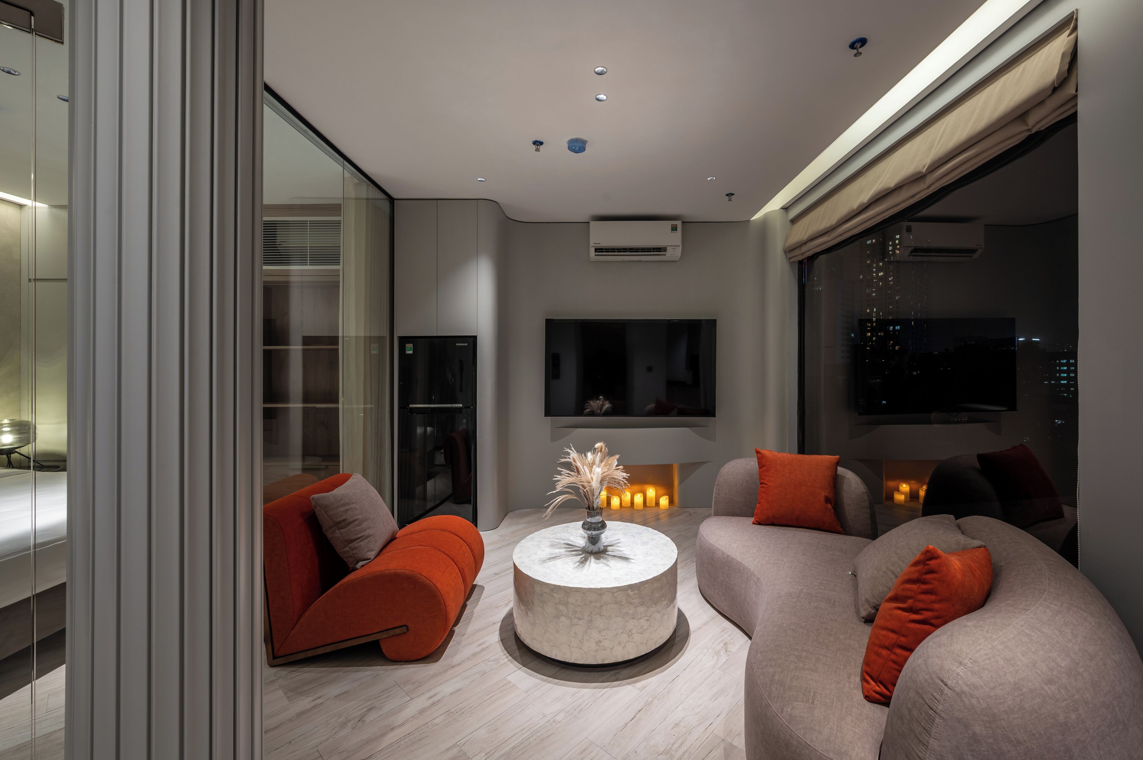 A modern living room with a round coffee table, two sofas, and a TV mounted on the wall.
