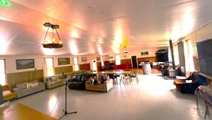 A spacious room with a high ceiling, multiple seating areas, and a large window. - Taringatura Backpackers (Dipton West)