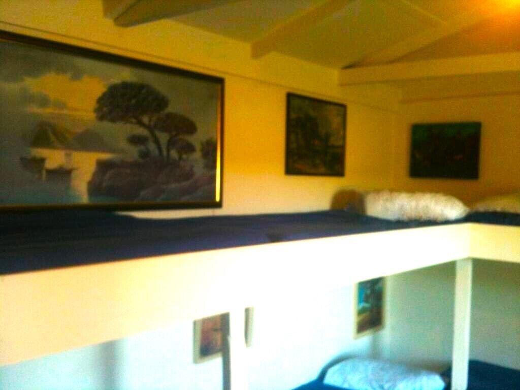 A room with bunk beds, a painting on the wall, and a small table.