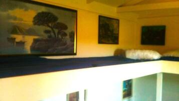 A room with bunk beds, a painting on the wall, and a small table.