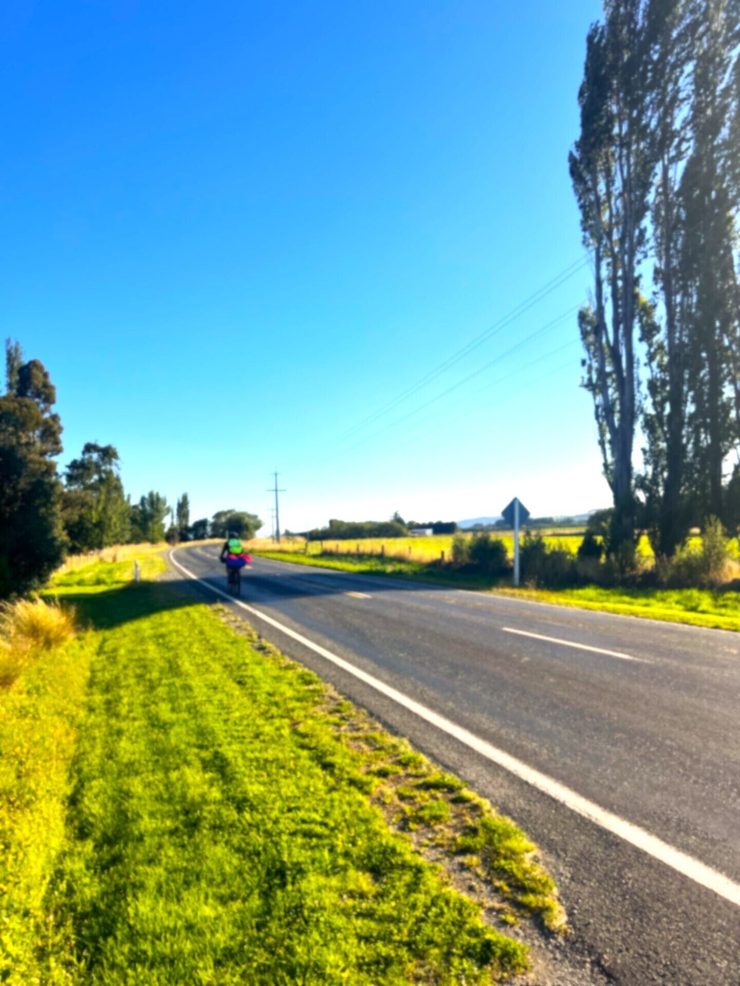 A rural road with a cyclist in the distance.
