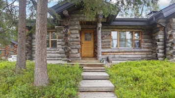 A log cabin with a wooden front door, a porch, and a pathway leading to the entrance.