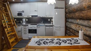 Una cocina rústica con paredes de madera, una escalera de madera y una mesa con mantel blanco y negro.