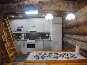 A compact kitchen with a wooden ceiling, a microwave, a stove, and a sink.