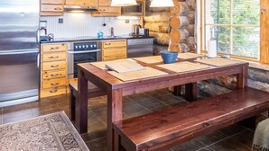 Eine moderne Küche mit Holzausziehtischen, einem Edelstahl-Kühlschrank, einem Kombi-Backofen und einem Esstisch mit Platzdeckchen.