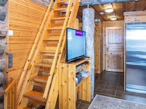 Een houten interieur met een televisie bevestigd aan een houten constructie, een koelkast en een trap.