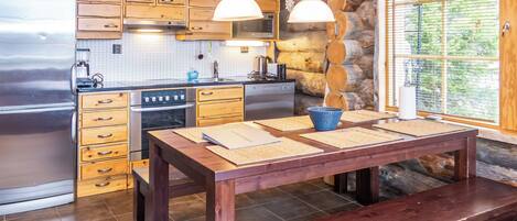 Eine moderne Küche mit Holzschränken, einem Edelstahlkühlschrank, einem Herd und einem Esstisch mit Tischsets.