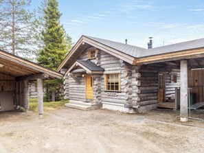 Une cabane en rondins avec un porche en bois et une cheminée.