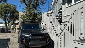 En svart SUV stod parkerad framför en byggnad med en trappa gjord av trä.