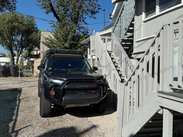 A black SUV parked in front of a building with a wooden staircase.