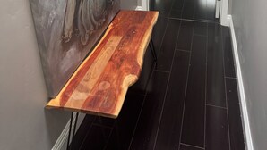 Un pasillo con un banco de madera, un cuadro de Buda y vista a un dormitorio con cama y cortinas.