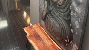 Una cocina moderna con electrodomésticos de acero inoxidable, un banco de madera y un cuadro grande de una figura sentada.