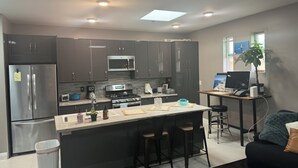 Una cocina moderna con gabinetes oscuros, electrodomésticos de acero inoxidable y una isla central con taburetes de bar.