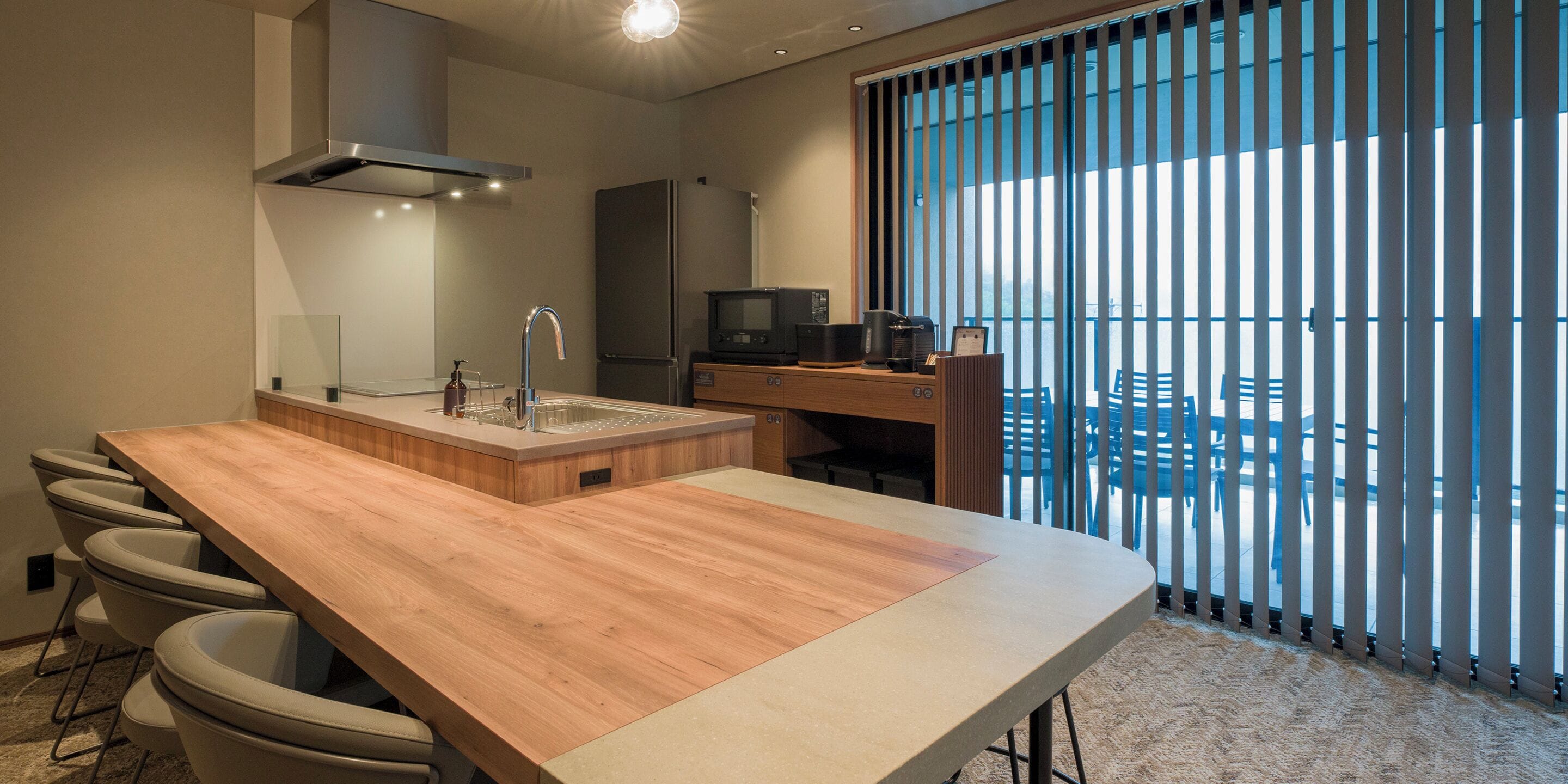 Cozinha moderna com bancada de madeira, banquetas, pia embutida e micro-ondas.