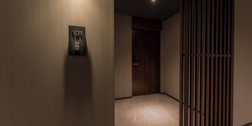 Un pasillo con una puerta marcada '101', un interruptor de luz en la pared y un marco de puerta de madera.