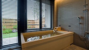 A modern bathroom with a bathtub, shower, and a window with blinds. - Rakuten STAY TERRACE Hakone Kowakudani (Hakone)