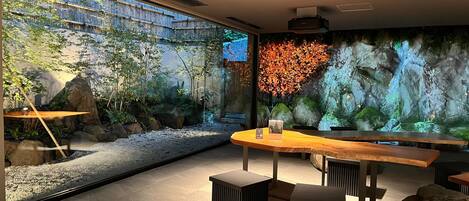 A modern interior with a large window, a wooden table, and a seating area with stools.