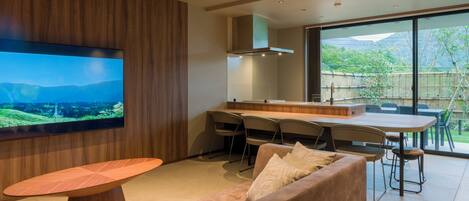 A modern kitchen with a large TV, wooden paneling, and a dining area with chairs and a table.