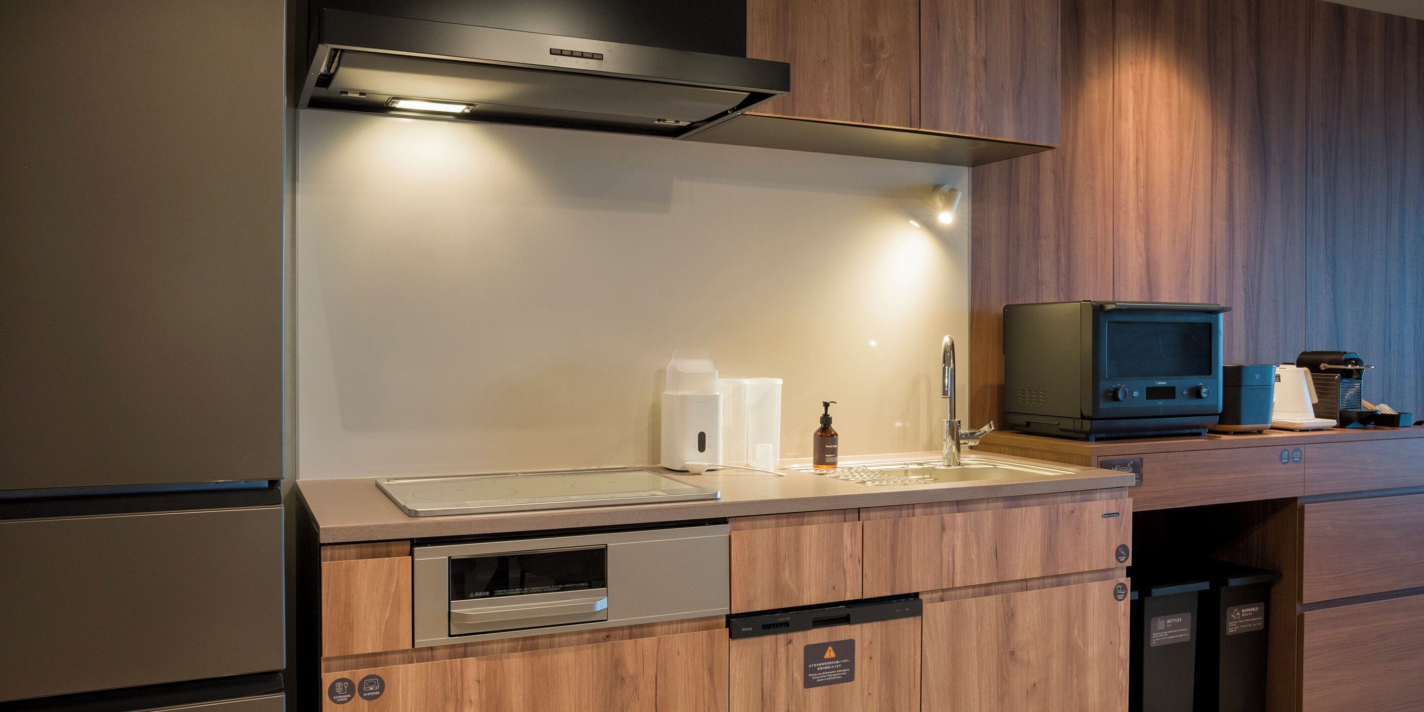 A modern kitchen with a built-in oven, a stainless steel sink, and a microwave.