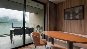 Un espace repas moderne avec une table et des chaises en bois, une cloison en verre et une vue sur l’extérieur.