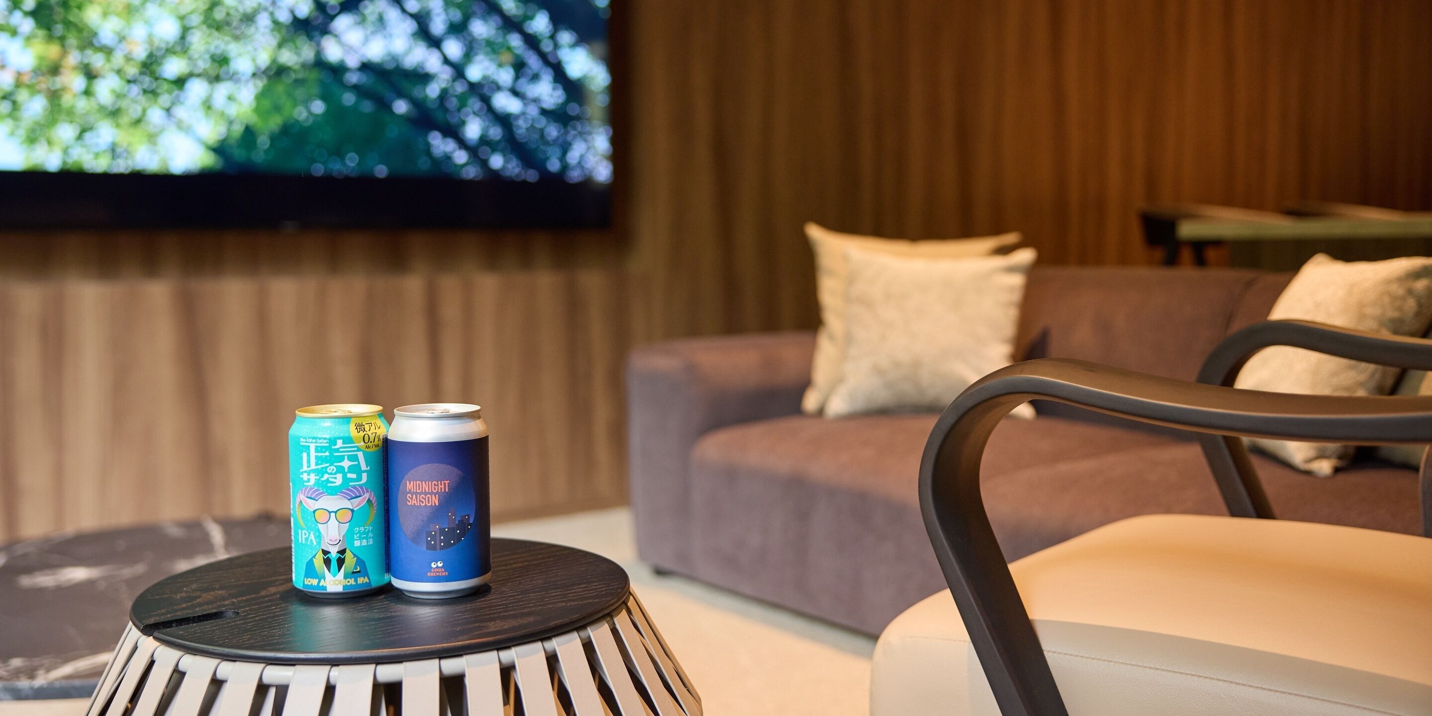 A room with a sofa, a television mounted on the wall, and two cans on a table.
