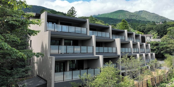 A modern multi-story building with balconies, surrounded by lush greenery and mountains in the background. - Rakuten STAY TERRACE Hakone Kowakudani (Hakone)