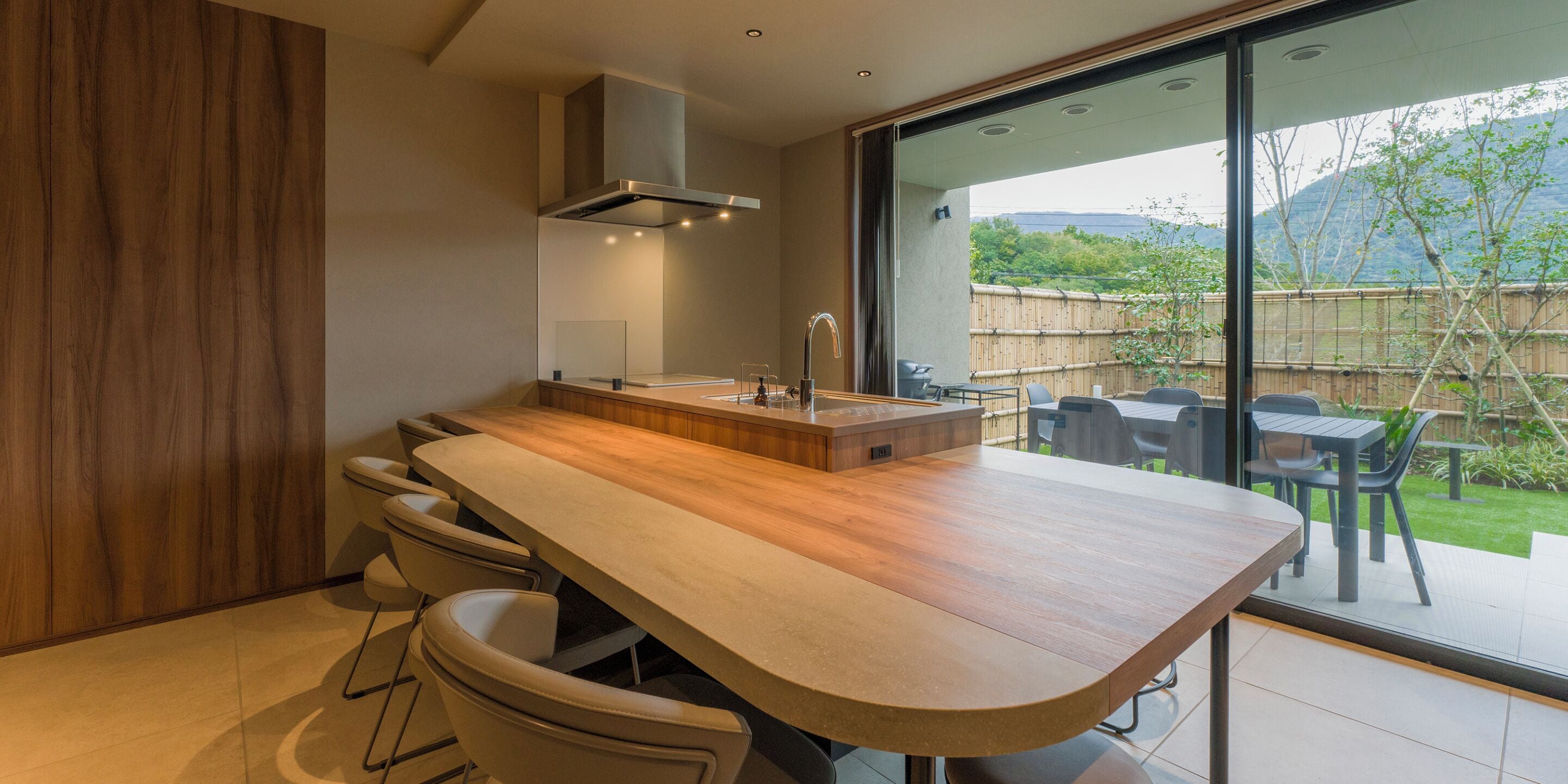Een moderne keuken met een houten aanrechtblad, een inbouwbar en een groot raam met uitzicht op een tuin.