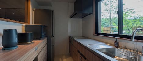 Una cocina moderna con horno empotrado, microondas y un lavamanos de acero inoxidable.