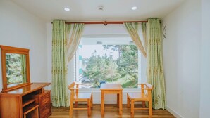 A room with a wooden table and chairs, a TV stand, and a window with curtains.