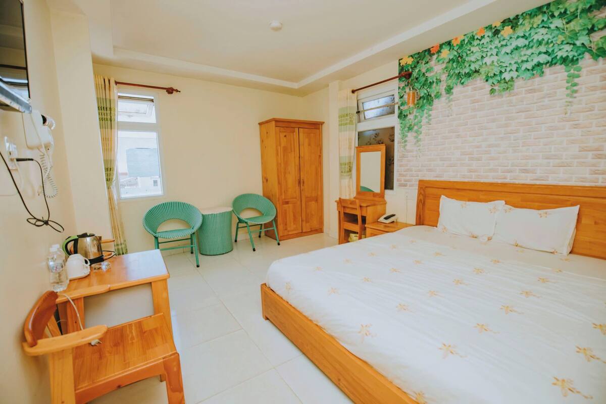 A bedroom with a wooden bed, a desk, a chair, and a wardrobe.
