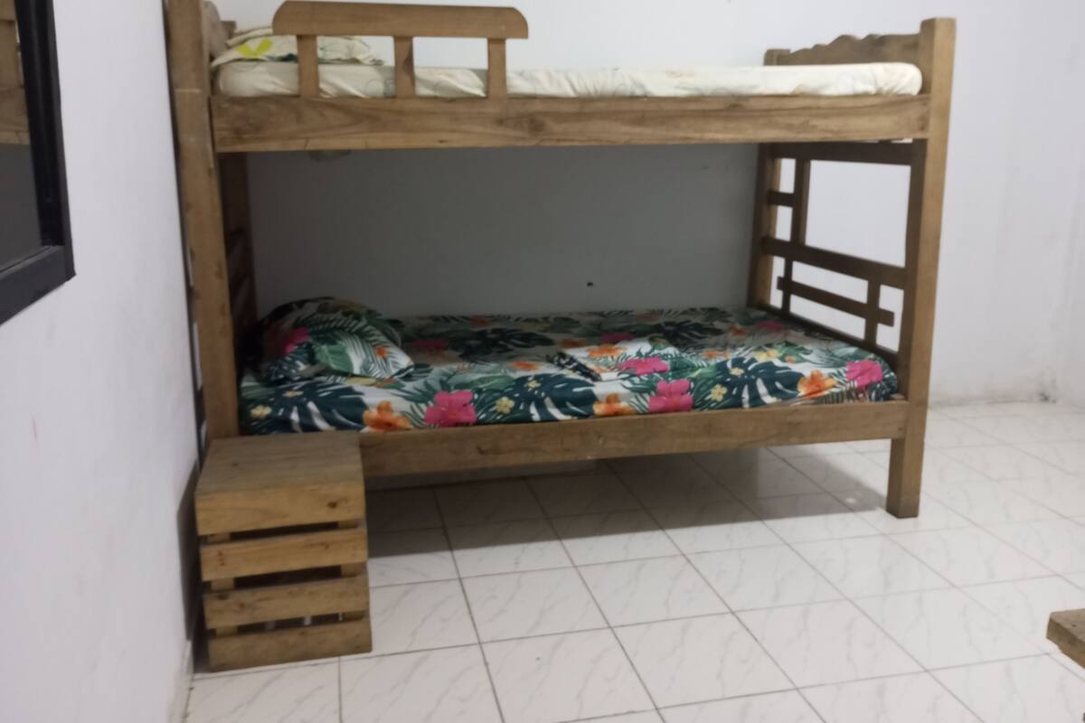 Un lit superposé avec une couvre-lit à motifs floraux et une échelle en bois.