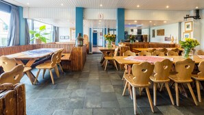A restaurant with wooden tables and chairs, a blue accent wall, and a view of the outside.