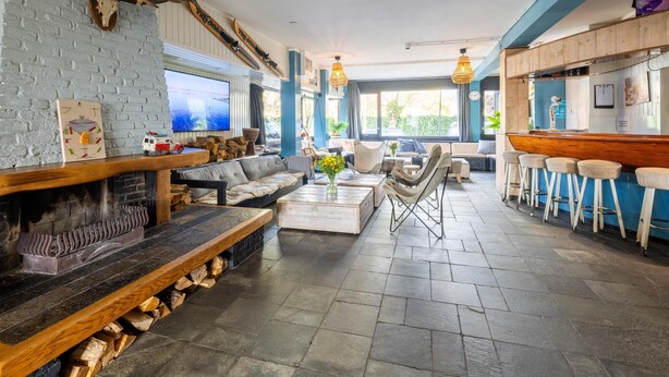 A cozy, rustic interior with a fireplace, comfortable seating, and a bar area.