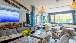 A cozy lounge area with a large flat-screen TV, wooden furniture, and a view of the outdoors.