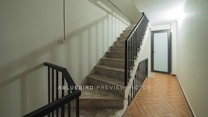 A staircase with a black railing, a light fixture above, and a door at the top. - Laura house (Hanoi)