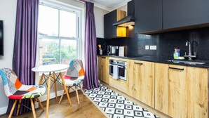A modern kitchen with wooden cabinets, a black countertop, and a window with purple curtains.