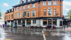 A brick building with a sign for "The Redford" hotel rooms, a bike parking area, and a street with wet pavement.