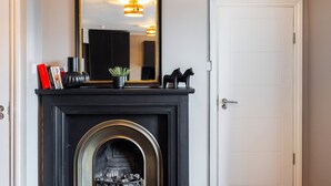 A room with a black fireplace, a white door, and a mirror above the fireplace.