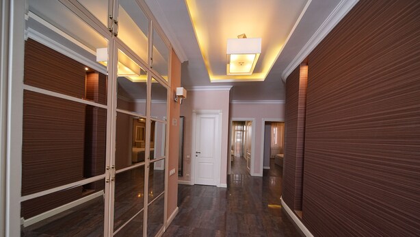 A hallway with a wooden floor, a white door, and a glass partition with a metal frame.