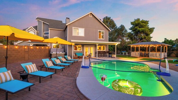 Un jardin avec une piscine, des chaises longues et un patio couvert.