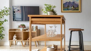 A wooden cart with wheels, a small stool, and a painting on the wall. - Cozy Corner Apartment (Cape Town)