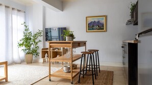 A modern kitchen with a wooden table, stools, and a potted plant. - Cozy Corner Apartment (Cape Town)