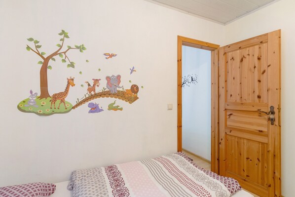 A bedroom with a bed, a wooden door, and a wall decal of animals.