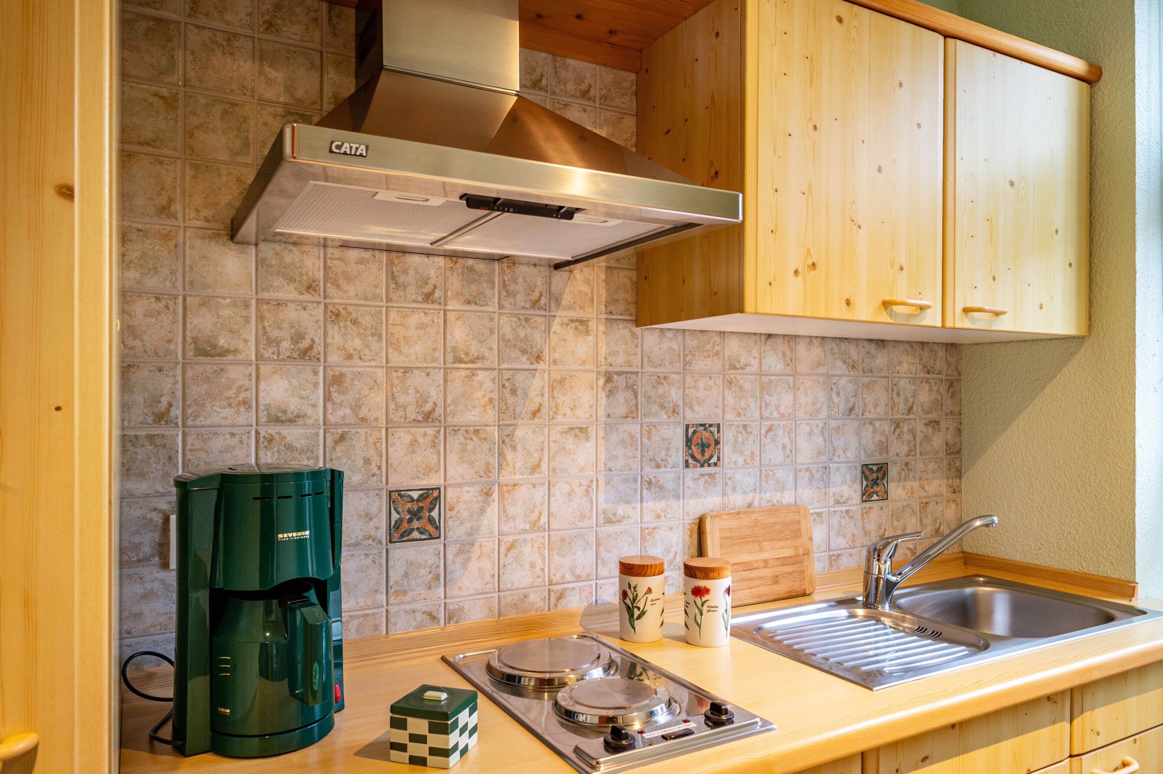 Une cuisine équipée d’une machine à café, d’une cuisinière, d’un évier et de meubles de rangement en bois.