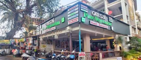 A restaurant with a signboard advertising various services like AC rooms, breakfast, lunch, dinner, and free WiFi.