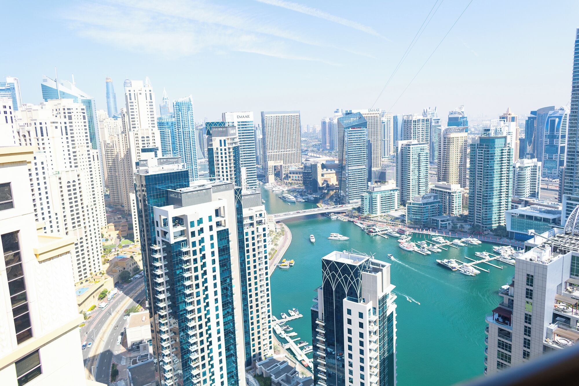A high-rise cityscape with modern architecture, a marina with boats, and a clear sky.