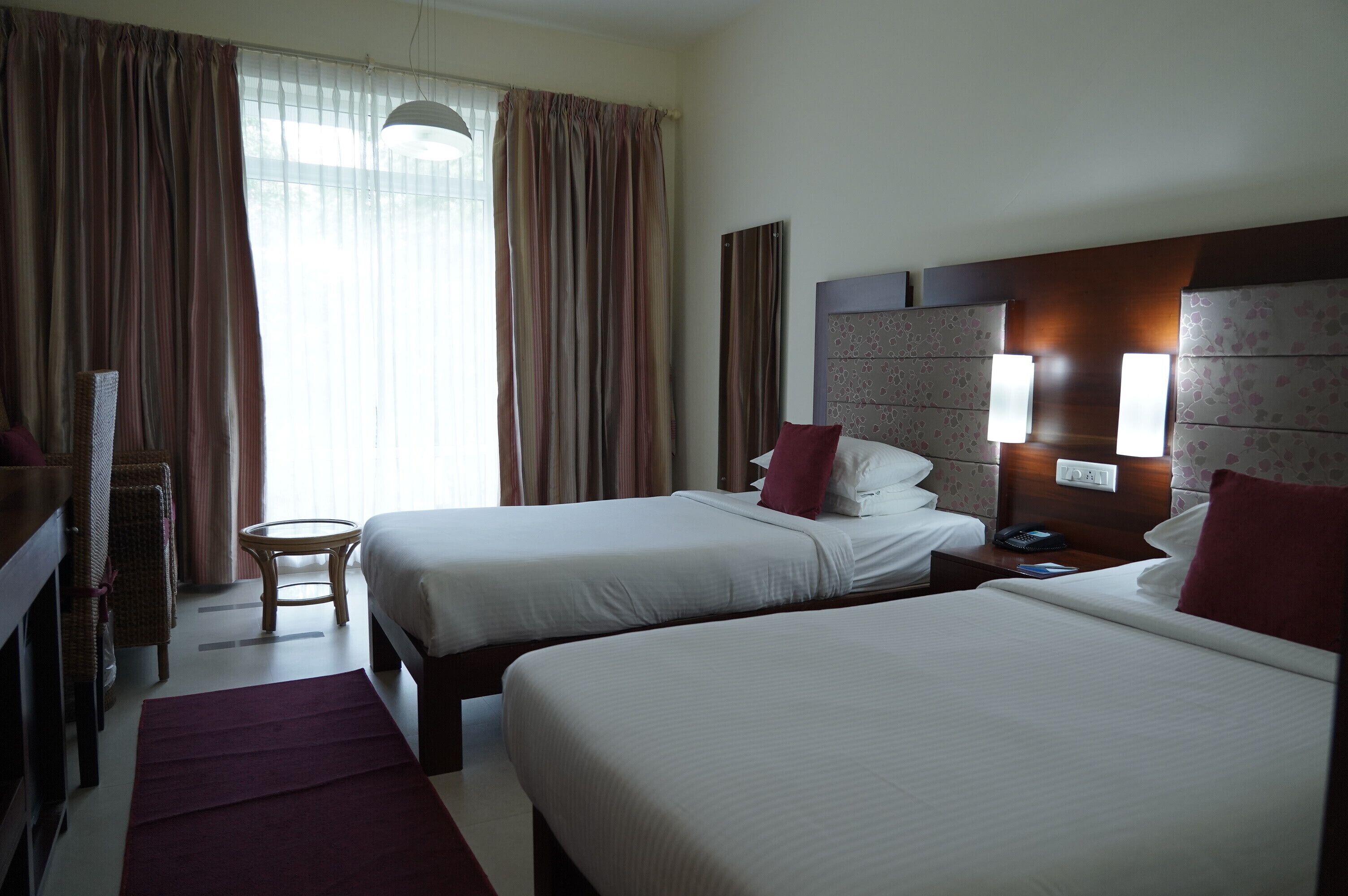 Ein Hotelzimmer mit zwei Betten, einem kleinen runden Tisch und einem Fernseher.