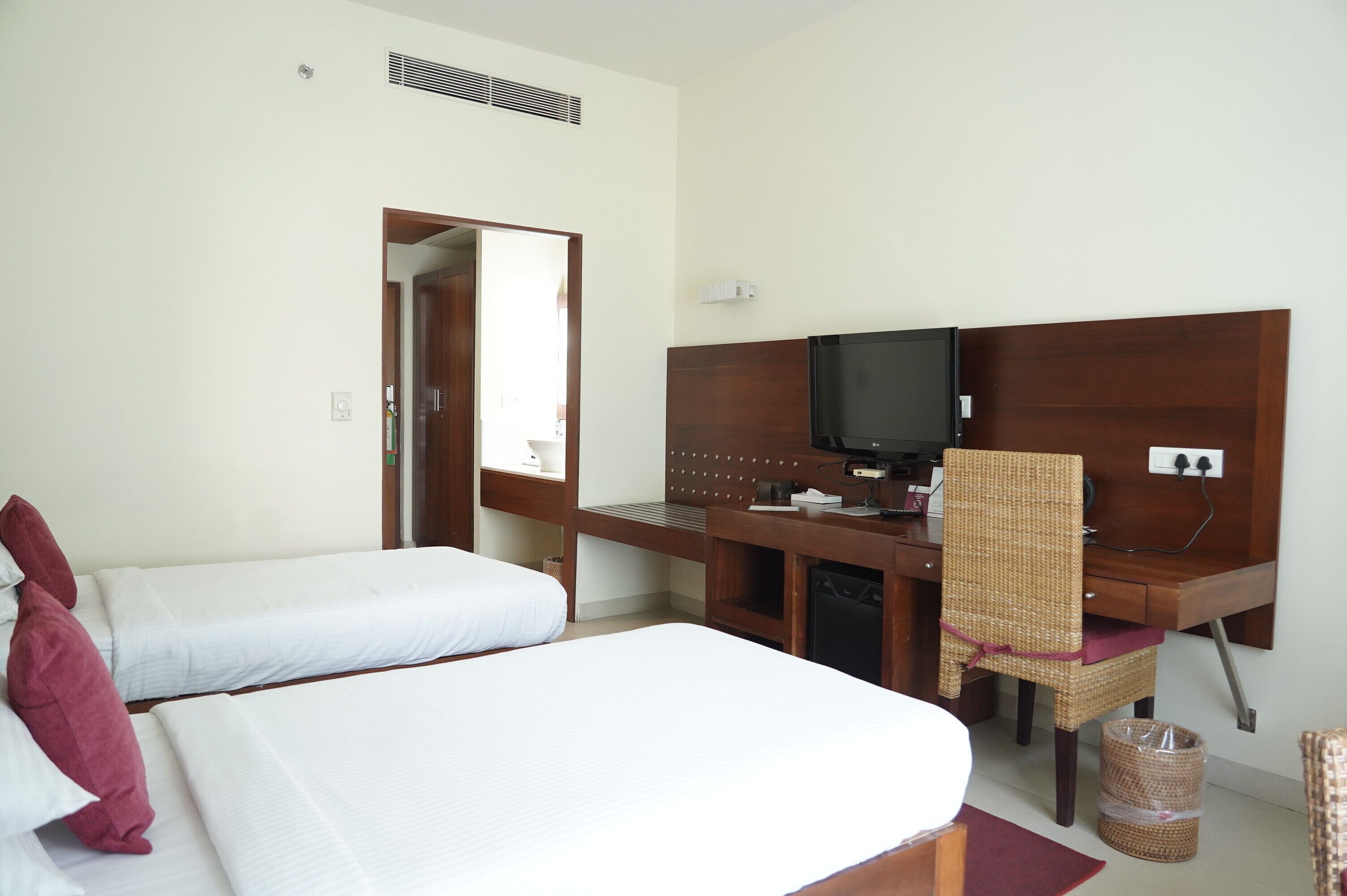 Una habitación de hotel con dos camas individuales, un escritorio con televisor y una silla.