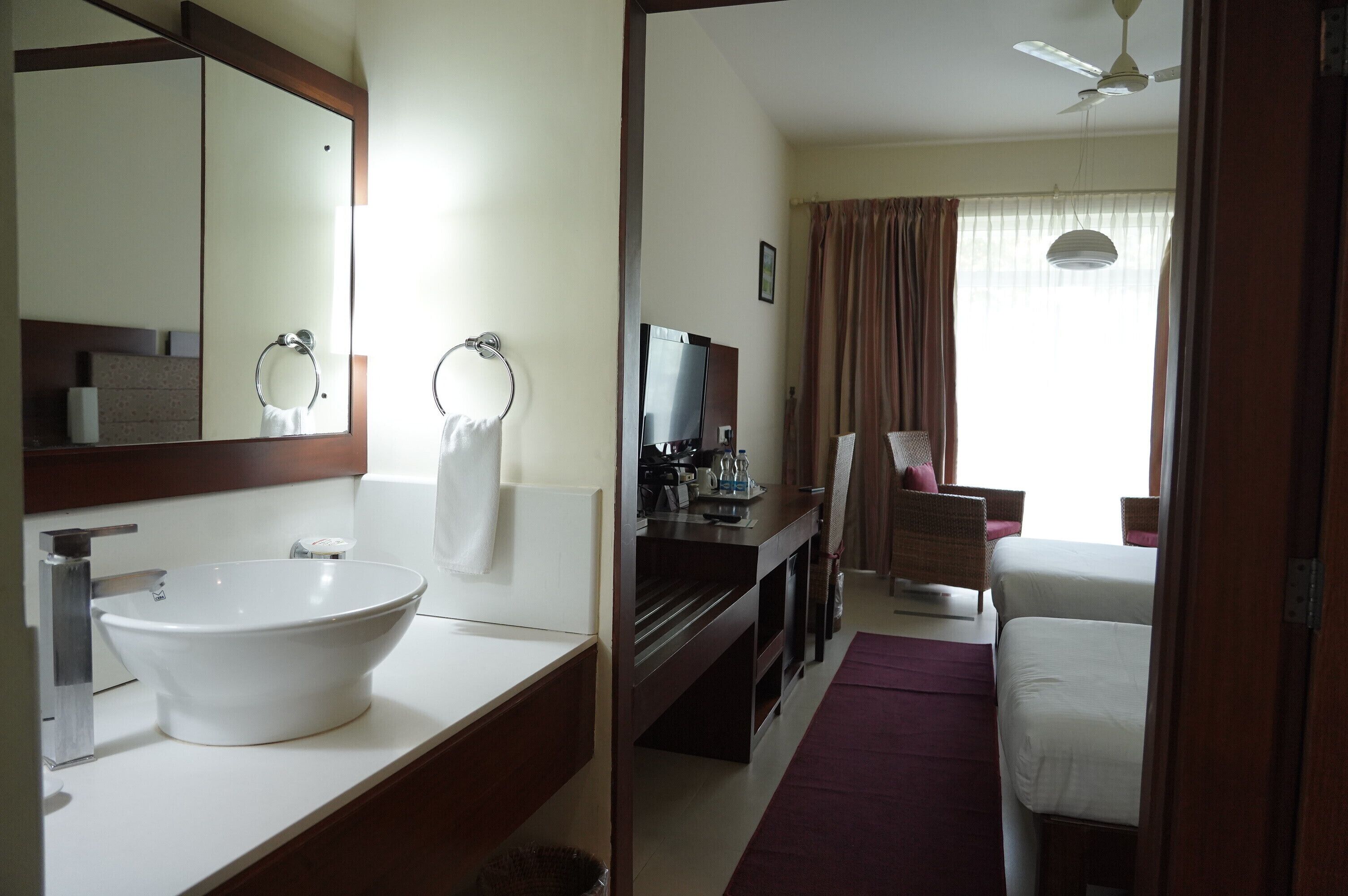 Un baño de hotel con un lavamanos grande, un espejo y un televisor.